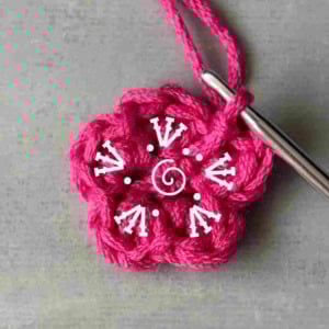 Small flower crochet applique pink with crochet symbols written on it