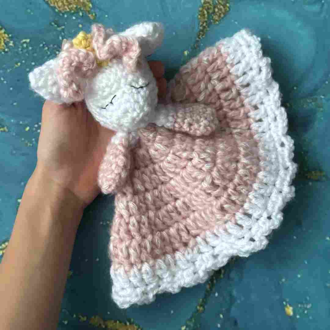 Girl holding unicorn baby lovey on blue background