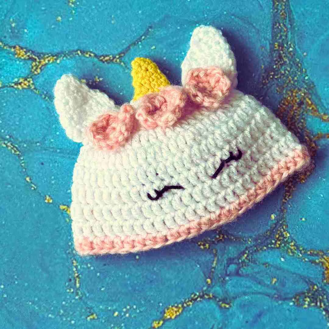 a white and pink crocheted baby beanie unicorn